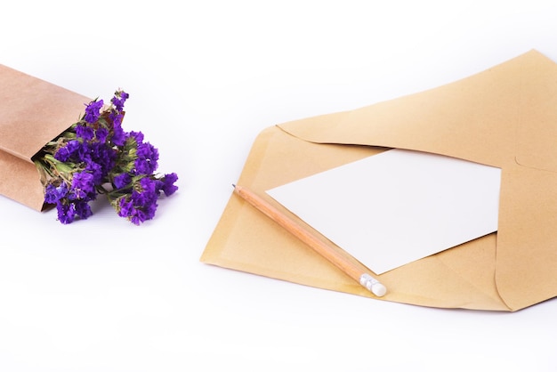 Photo blue dried flowers in brown paper bag and postal envelope on the white background close up top view copy space isolate