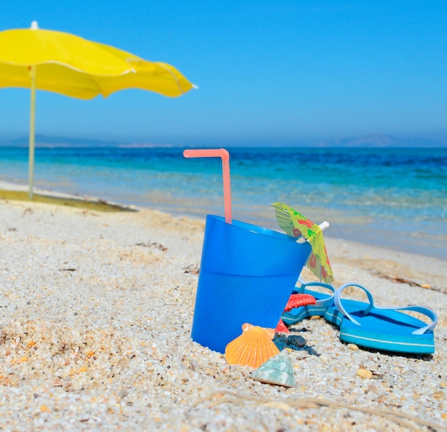 熱帯のビーチで青い飲み物と黄色のパラソル