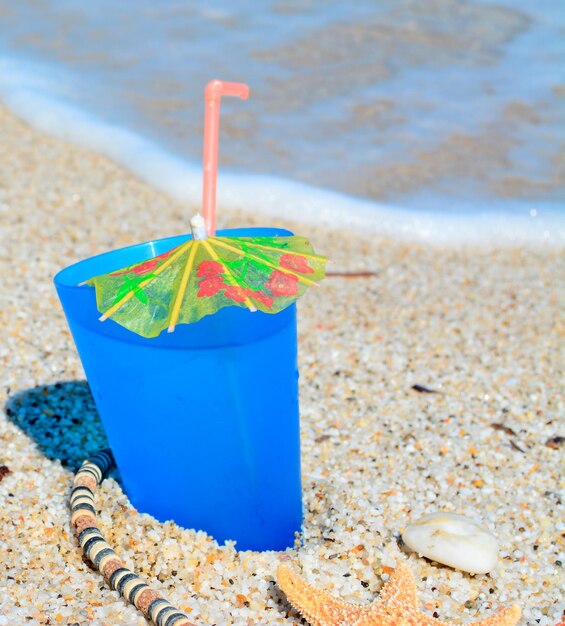 Blue drink with shells and necklace by the shore