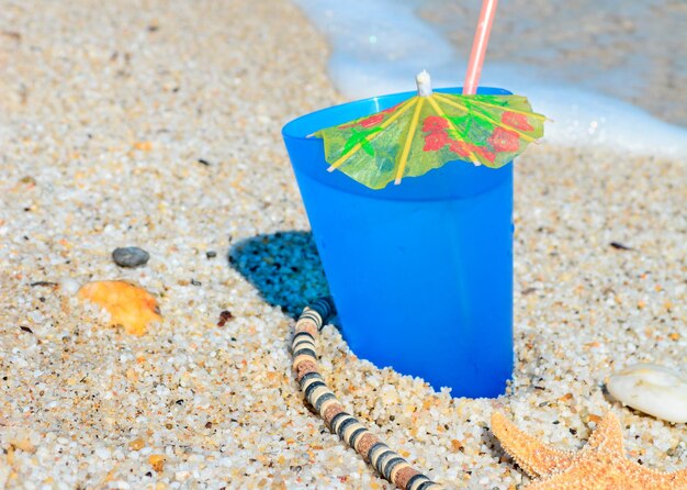 Blue drink with shells and necklace by the shore