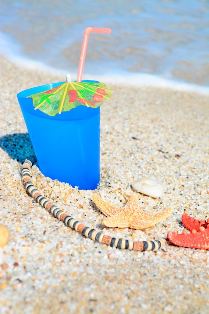 Blue drink with shells and necklace by the shore