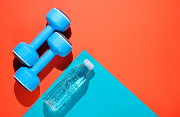 Blue dumbbells and a bottle of water