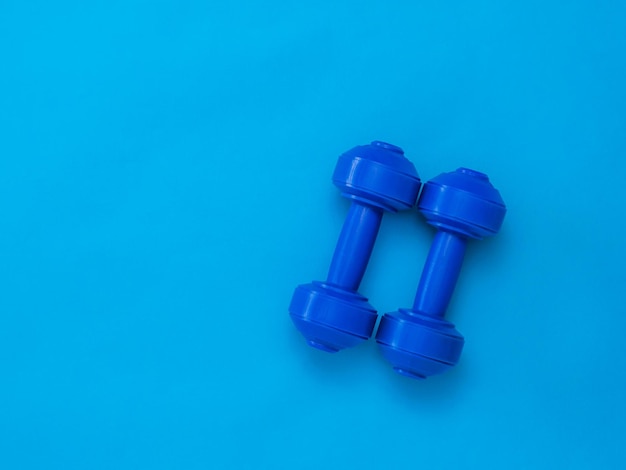 Blue dumbbells for training on a blue background. Accessories for fitness and weightlifting.