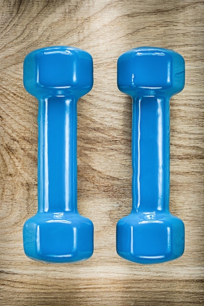 Blue dumbbells on wooden board fitness concept.