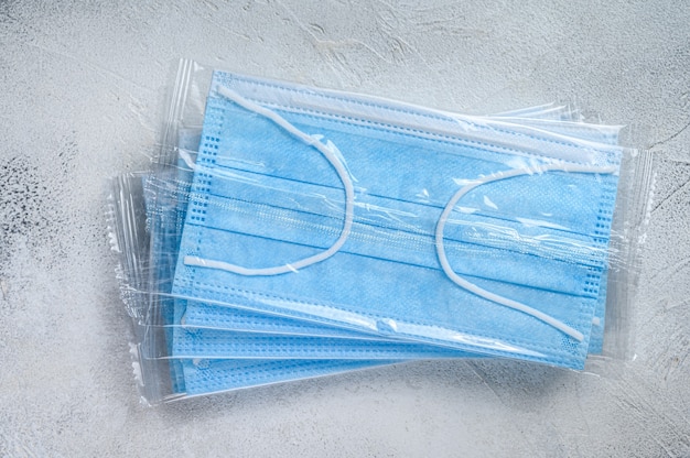 Blue ear loop surgical face masks. Disposable procedural face mask with malleable nose clip. White background. Top view.