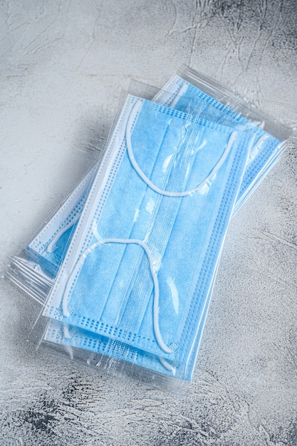 Blue ear loop surgical face masks. Disposable procedural face mask with malleable nose clip on white table. Top view.