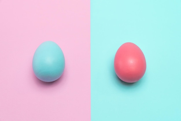 Blue easter egg on the left side and the pink one on the right side. On the punchy pastel background.