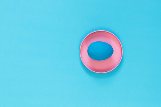 Photo the blue easter egg lies in a brightly pink metal box blue background copy space