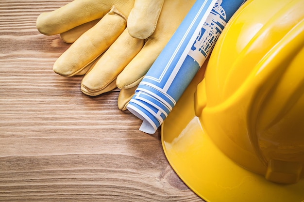 Blue engineering drawing building helmet safety gloves on wooden board construction concept