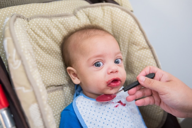 Blue eyed baby boy eating - In baby stroller