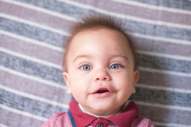 Blue-eyed baby boy lying on the bed