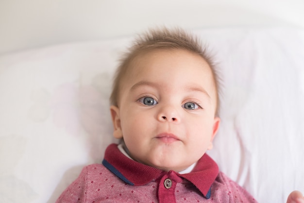 ベッドの上に横たわる青い目の赤ん坊の男の子