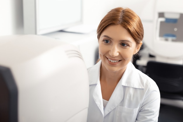 Blue-eyed eye doctor. Beautiful blue-eyed eye doctor with brassy hair smiling while working