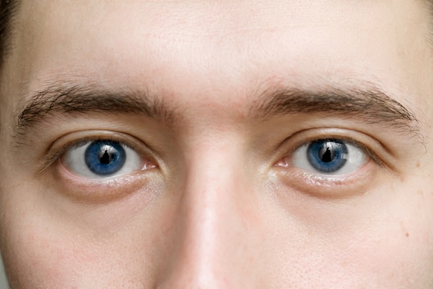 Occhi blu di un uomo da vicino. il concetto di ottica e medicina oftalmologica. lo sguardo maschile