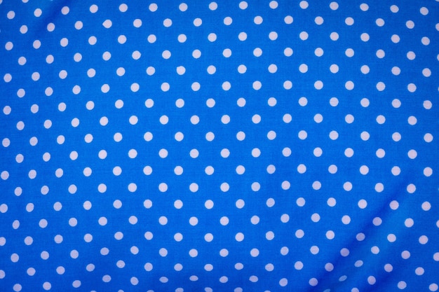Blue fabric in polka dots pattern background. Modern textile texture. Detail of clothing.