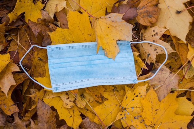 Blue face mask lies in autumn yellow leaves in close-up