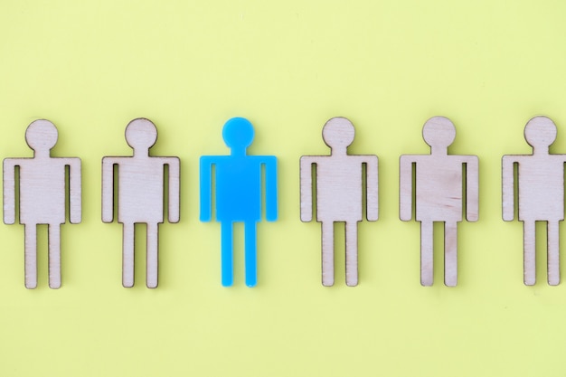 Blue figurine of man lying among wooden on yellow background closeup