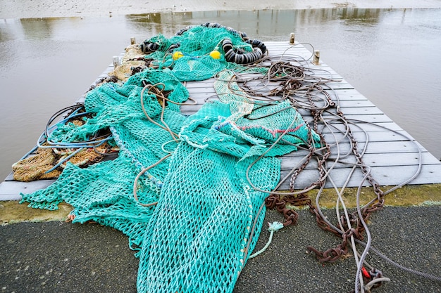 Blue fishing net on a pontoon with its ropes and floats covered with morning frost