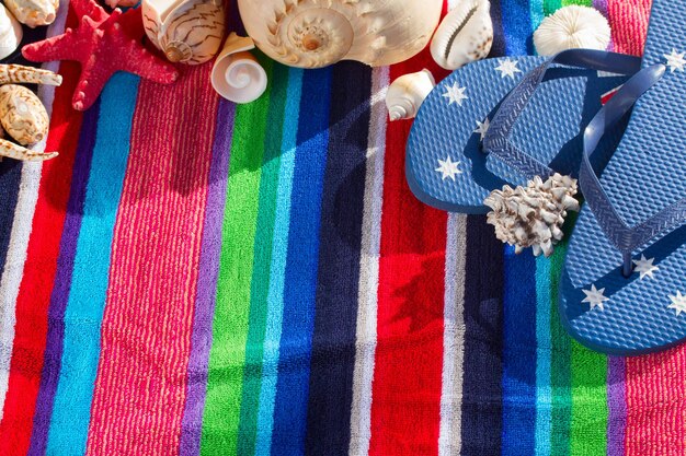 Blue flip flops on striped  beach towel with sea shells