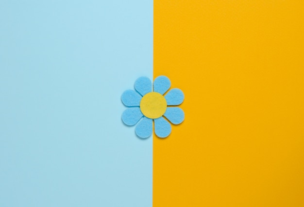 Blue flower made of felt on a blue and orange background. 