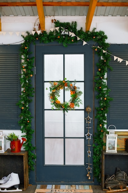 The blue front door is outside the house decorated with a christmas