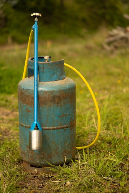 A blue gas bottle and a burner on grass