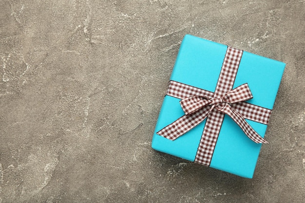 Blue gift box with brown ribbon on grey background Space for text