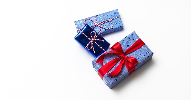 Синяя подарочная коробка с красными лентами на белом фоне