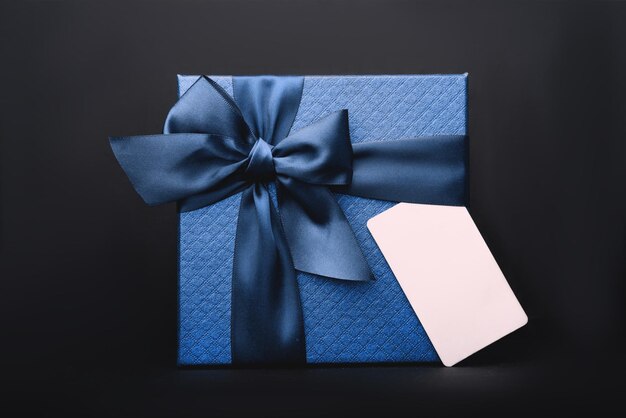 A blue gift box with a tag on the black background