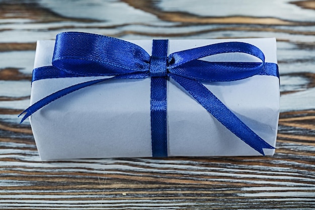 Blue gift box with tied bow on vintage wooden board