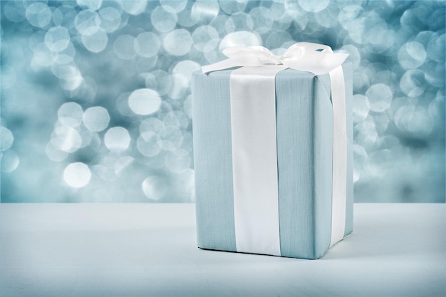 Blue gift box with white bow on blurred background