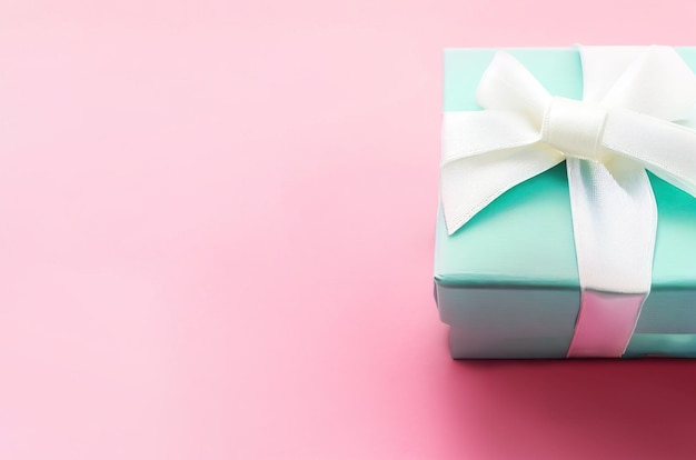 A blue gift box with a white ribbon on a pink background.