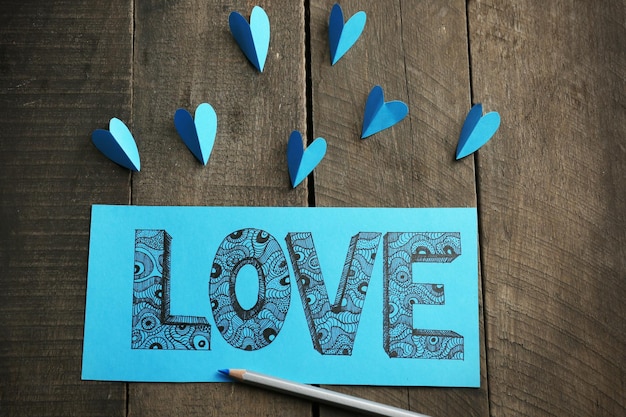 Photo blue gift card with love doodle drawing on wooden background