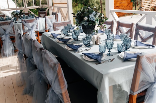 Blue glasses plates and utensils on a festive table with flowers Serving and decor of the wedding table