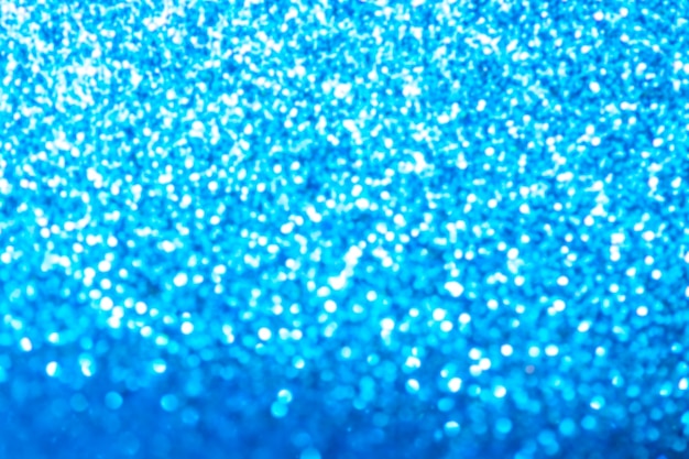 Blue glitter foil Christmas background. Shiny metal blue foil texture abstract defocused background. Sparkle glitter texture with bokeh lights.