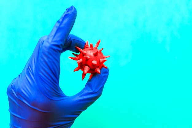 Голубая рука с перчатками держит вирус коронавирус COVID-19