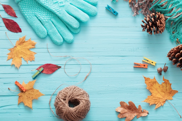 Blue gloves and autumn leaves on wooden background