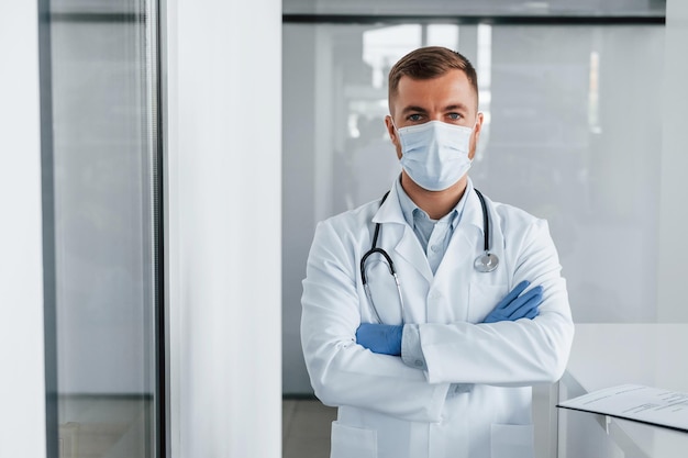 В синих перчатках Профессиональный медик в белом халате в клинике