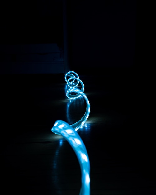 Blue glowing LED strip with cold light on a black background close-up, decorative lighting.