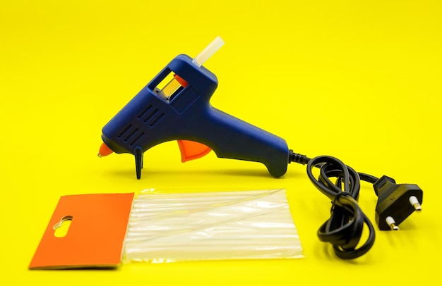 Blue glue gun closeup on a yellow background