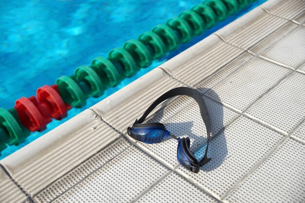 Синие очки для плавания на краю бассейна