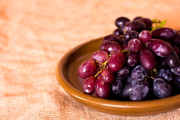 Photo blue grapes on a clay brown dish