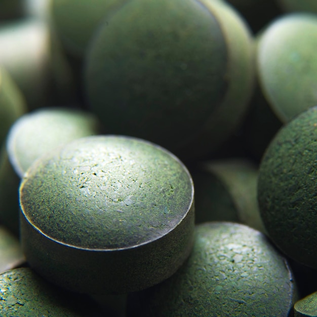 Blue green algae. Close up of natural organic spirulina tablets with focus at the foreground and blur effect