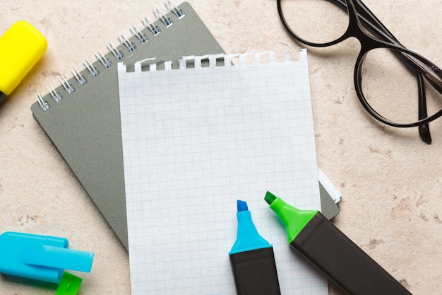空白のメモ帳用紙フラットの青と緑の蛍光ペンは机の上に横たわっていた