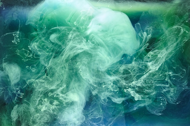 Fumo verde blu su sfondo di inchiostro nero, nebbia colorata, mare oceanico vorticoso astratto, pigmento di vernice acrilica sott'acqua