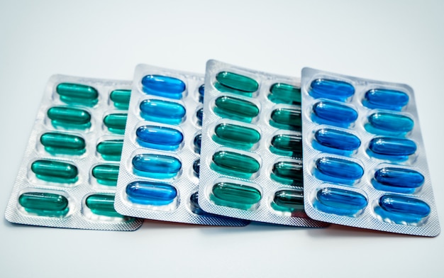 흰색 배경에 물집 팩에서 파란색과 녹색 부드러운 젤라틴 캡슐. 이부프로펜 및 나프록센 캡슐. 항염증제, 진통제. 진통제. 제약 산업.