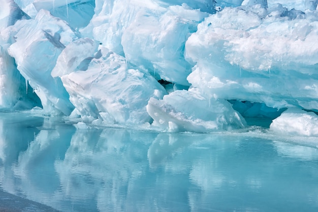 Фото Голубой гроулер кусок айсберга с отражением в спокойной воде. арктический океан