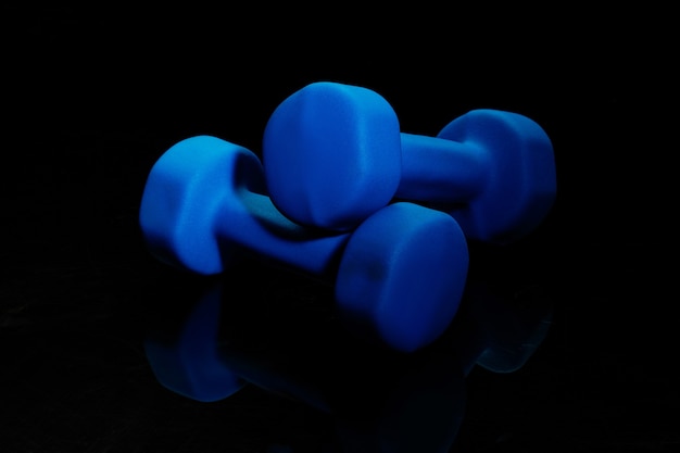 Pesi da palestra blu. attrezzatura sportiva professionale isolata su sfondo nero per studio. concetto di sport, leadership, competizione, stile di vita sano in movimento e azione, allenamento. primo piano, copyspace.