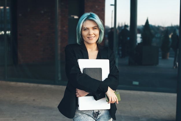 Blue haired blanke zakenvrouw poseren met haar laptop buiten terwijl