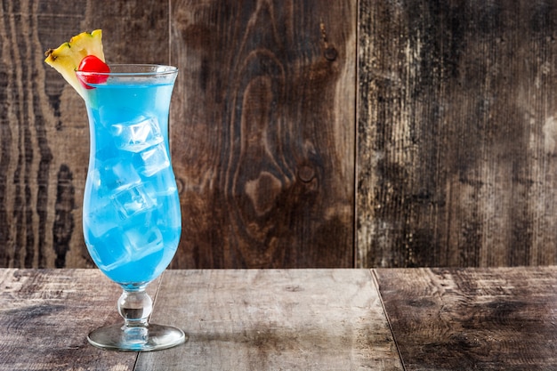 Blue Hawaiian cocktail on wooden table with copy space